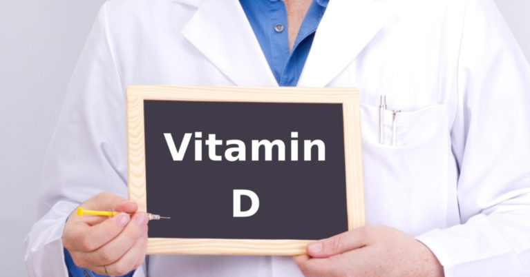 Person in lab coat holding Vitamin D sign