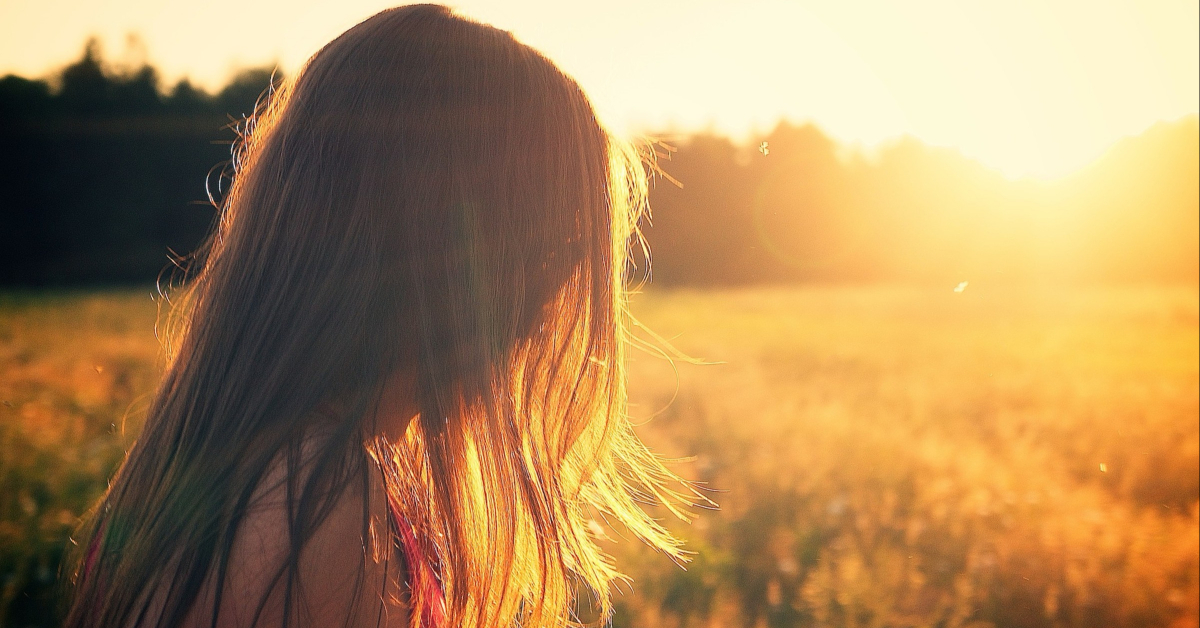 Girl looking over a golden field of sunlight